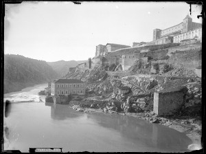 En la orilla del río, sobre los restos del Artificio, la Casa Elevadora de aguas edificada en 1873 para acoger una maquinaria a vapor que elevaría las aguas a la población. Fotografía de Casiano Alguacil tomada hacia 1880. Archivo Municipal de Toledo http://goo.gl/tlpnKI 